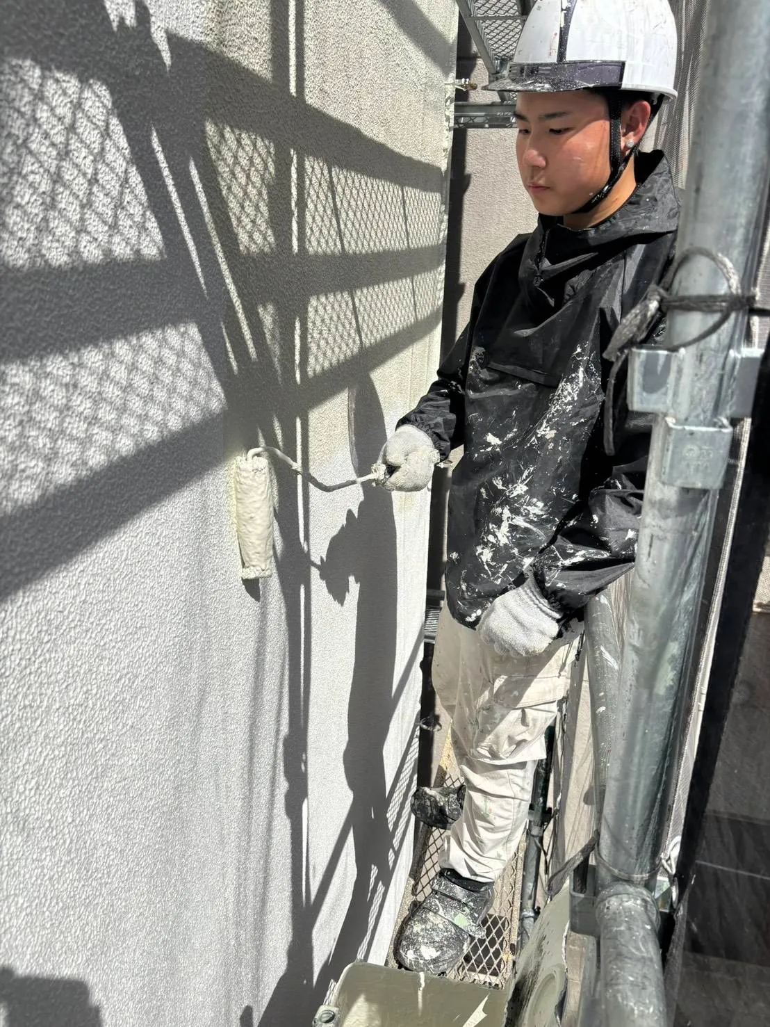 ローラーで外壁を塗装するスタッフ